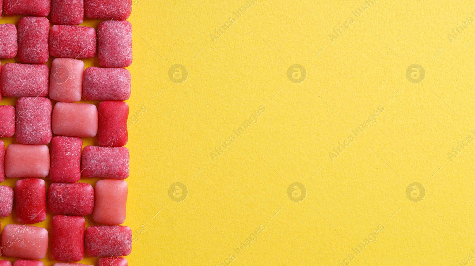 Photo of Sweet chewing gums on yellow background, flat lay. Space for text