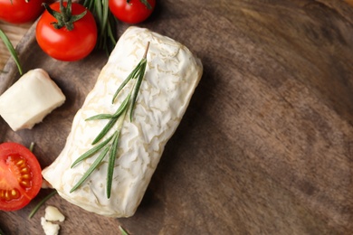 Delicious goat cheese with tomatoes and rosemary on wooden board, flat lay. Space for text