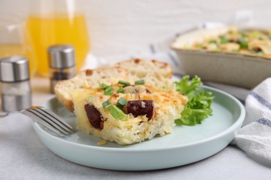 Photo of Tasty sausage casserole with green onion served on light grey table, closeup