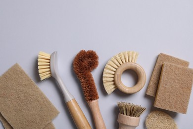 Photo of Cleaning brushes and sponges on grey background, flat lay