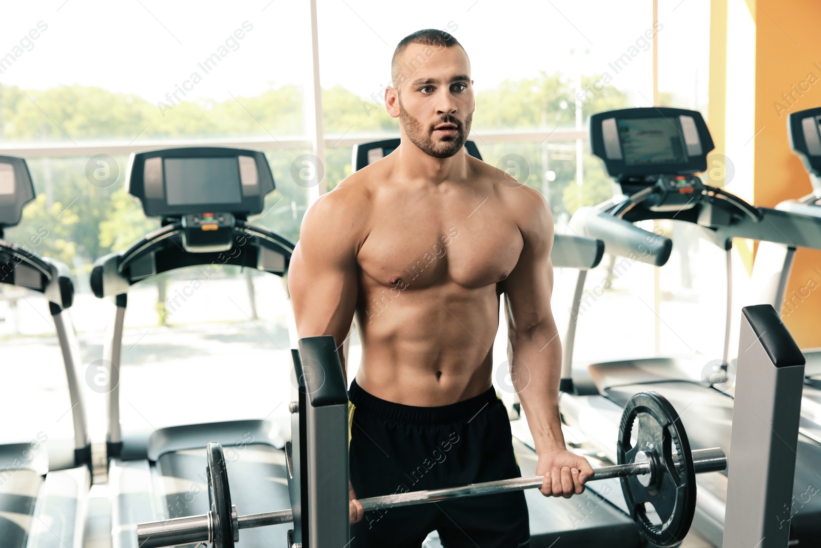 Photo of Strong young man lifting barbell in gym