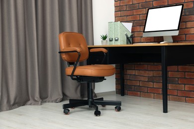 Stylish office interior with comfortable chair, desk and computer