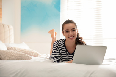 Young woman working with laptop on bed at home