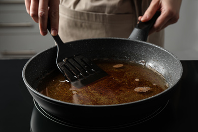Photo of Woman holding frying pan with used cooking oil, closeup