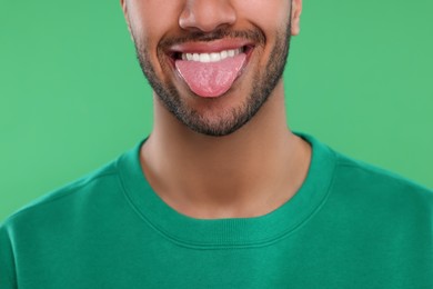 Photo of Happy man showing his tongue on green background, closeup
