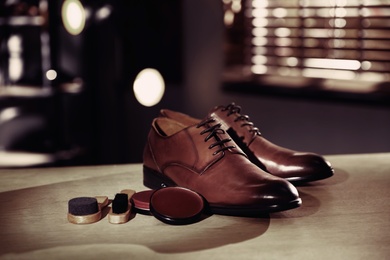 Image of Shoe care accessories and footwear on wooden table in workshop