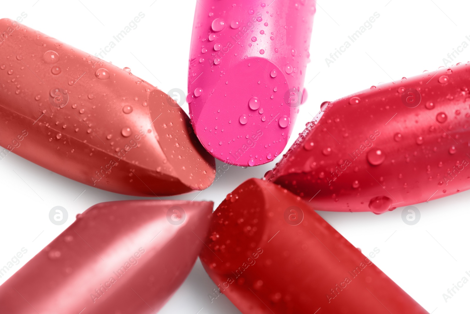 Photo of Many bright lipsticks with water drops on white background