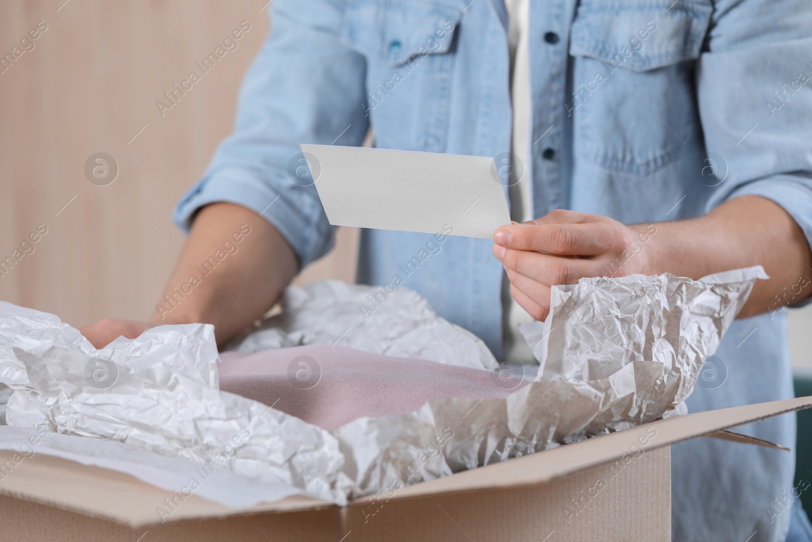 Photo of Man holding greeting card near parcel with Christmas gift, closeup