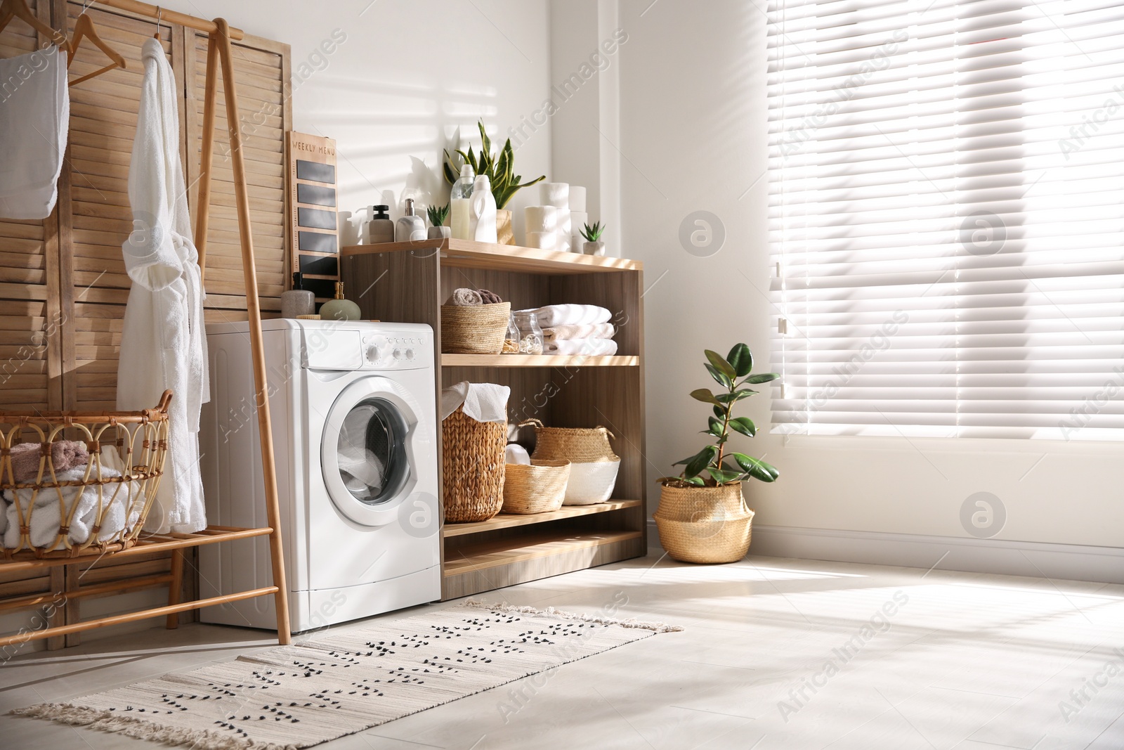 Photo of Modern washing machine and shelving unit in laundry room interior