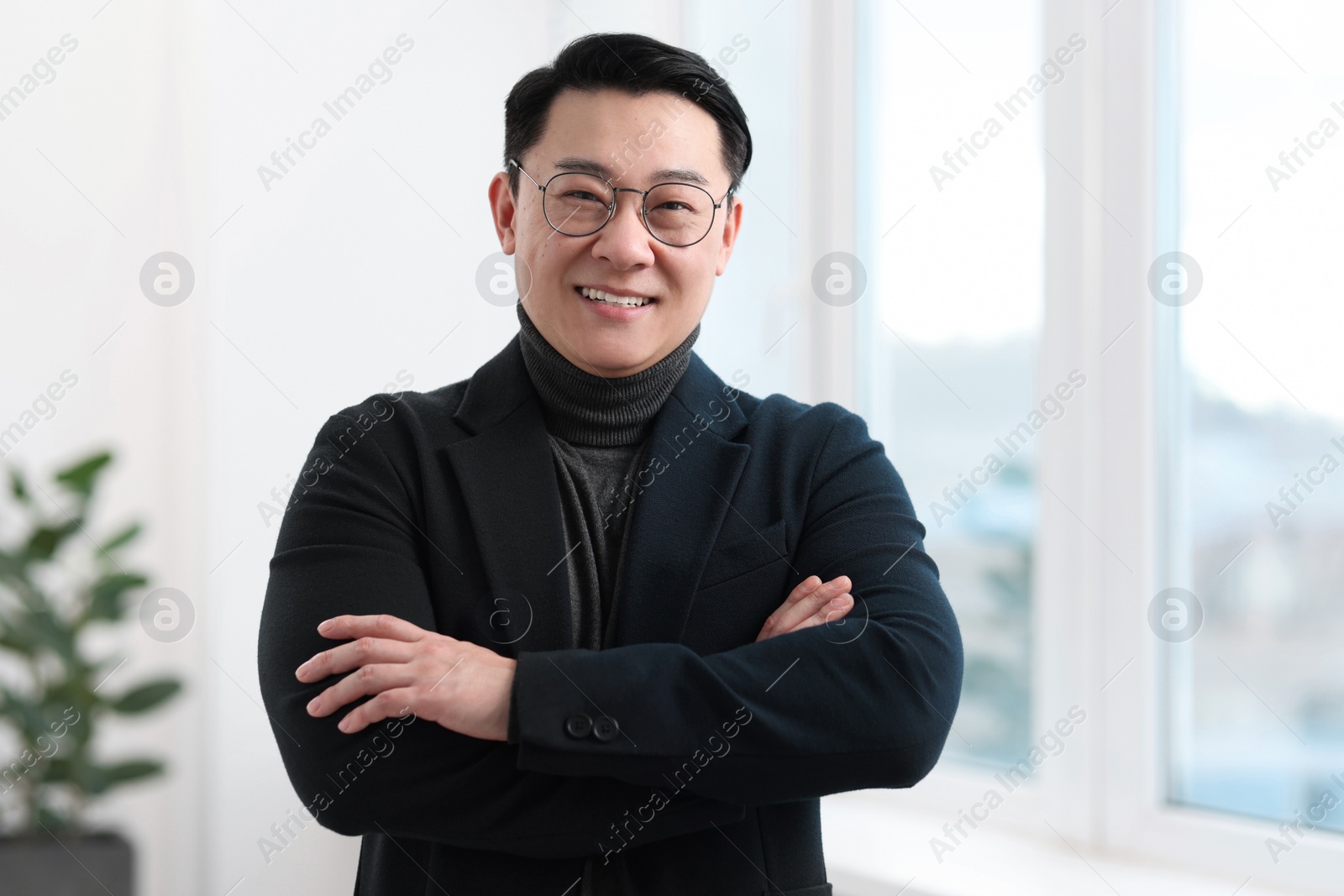 Photo of Portrait of smiling businessman with crossed arms in office