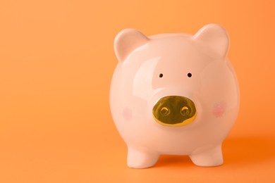 Photo of Ceramic piggy bank on orange background. Space for text