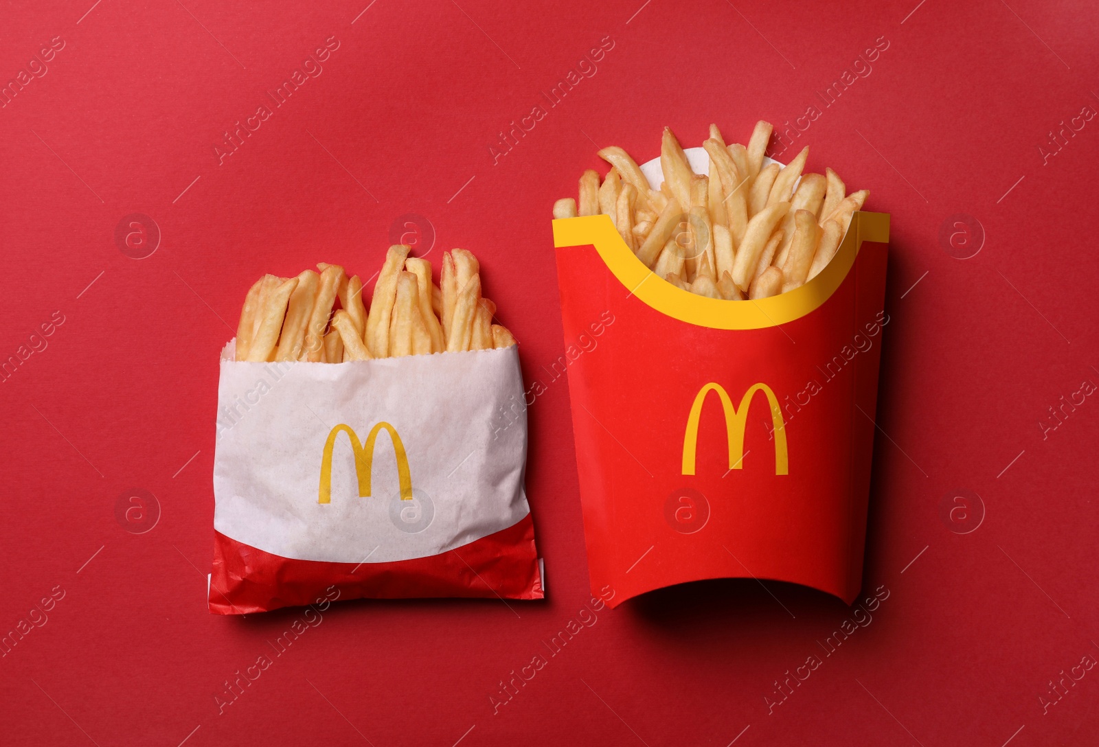 Photo of MYKOLAIV, UKRAINE - AUGUST 12, 2021: Small and big portions of McDonald's French fries on red background, flat lay