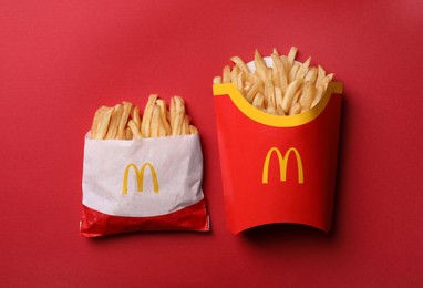 Photo of MYKOLAIV, UKRAINE - AUGUST 12, 2021: Small and big portions of McDonald's French fries on red background, flat lay