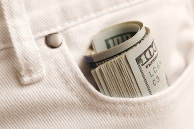 Photo of Dollar banknotes in pocket of white jeans, closeup. Spending money