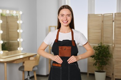 Portrait of professional hairdresser wearing apron in beauty salon