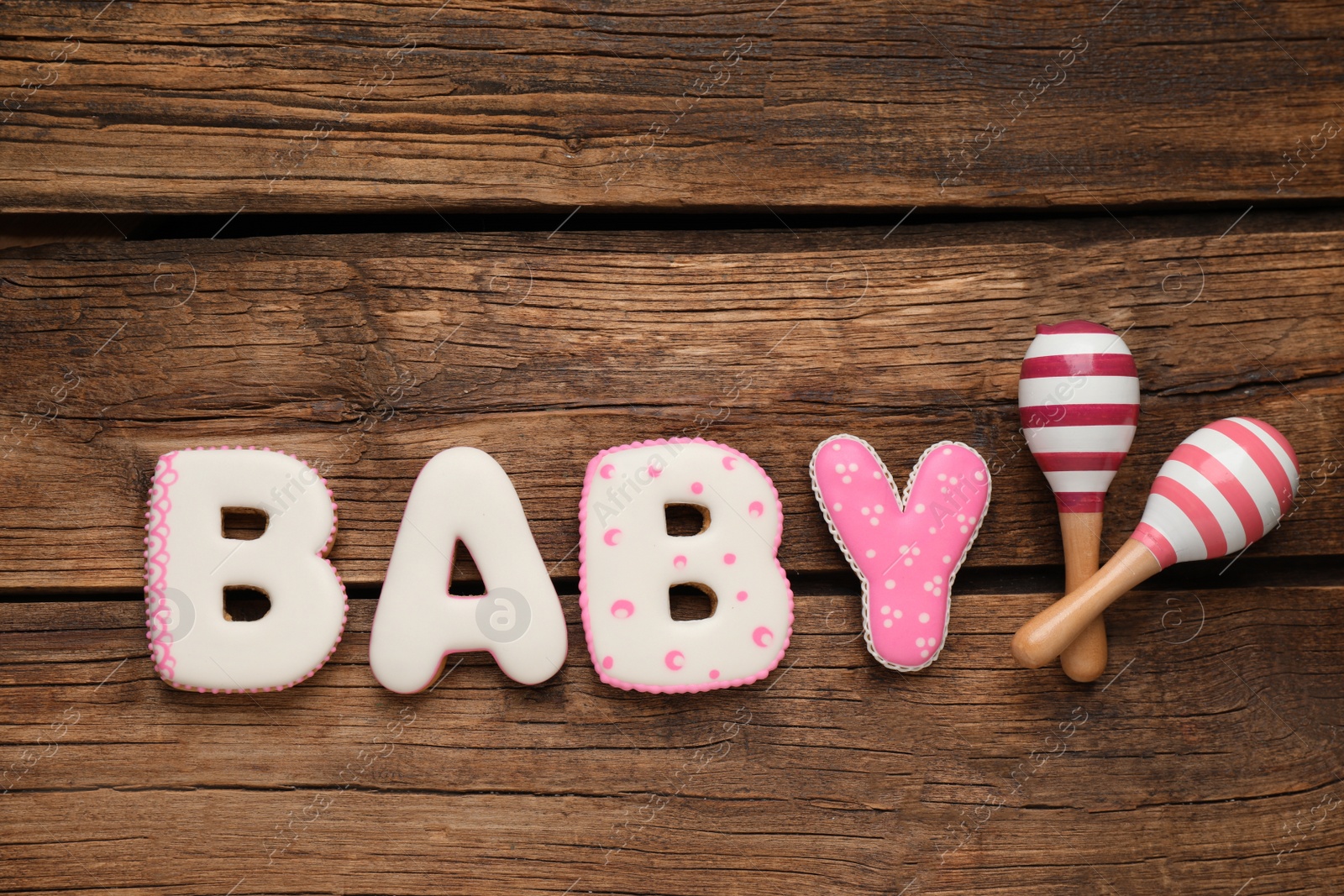 Photo of Word Baby made of tasty cookies and toys on wooden table, flat lay. Space for text