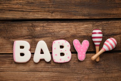 Photo of Word Baby made of tasty cookies and toys on wooden table, flat lay. Space for text