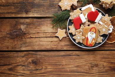 Photo of Tasty gingerbread cookies on wooden table, flat lay with space for text. St. Nicholas Day celebration