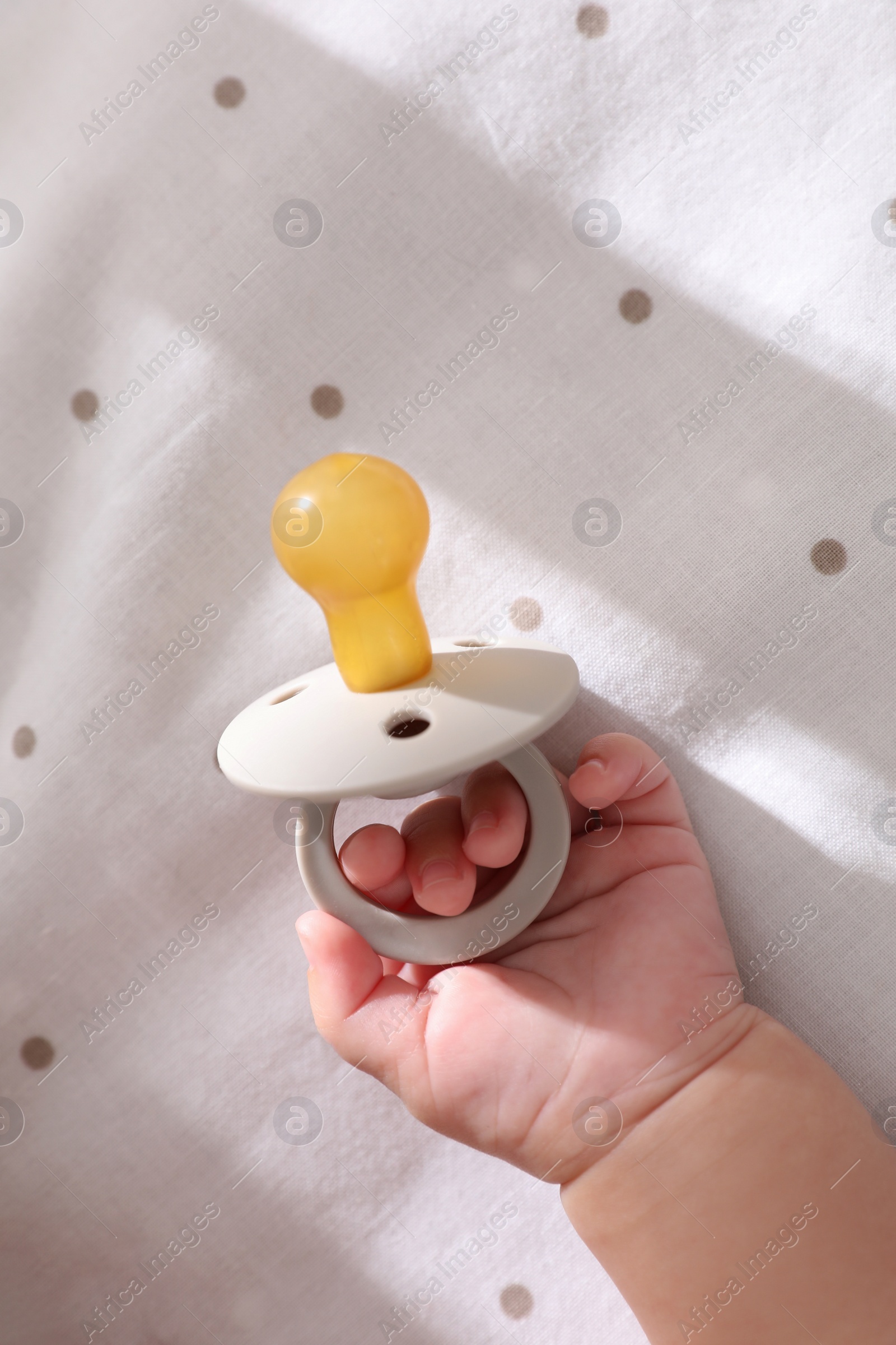 Photo of Little baby with pacifier in bed, closeup