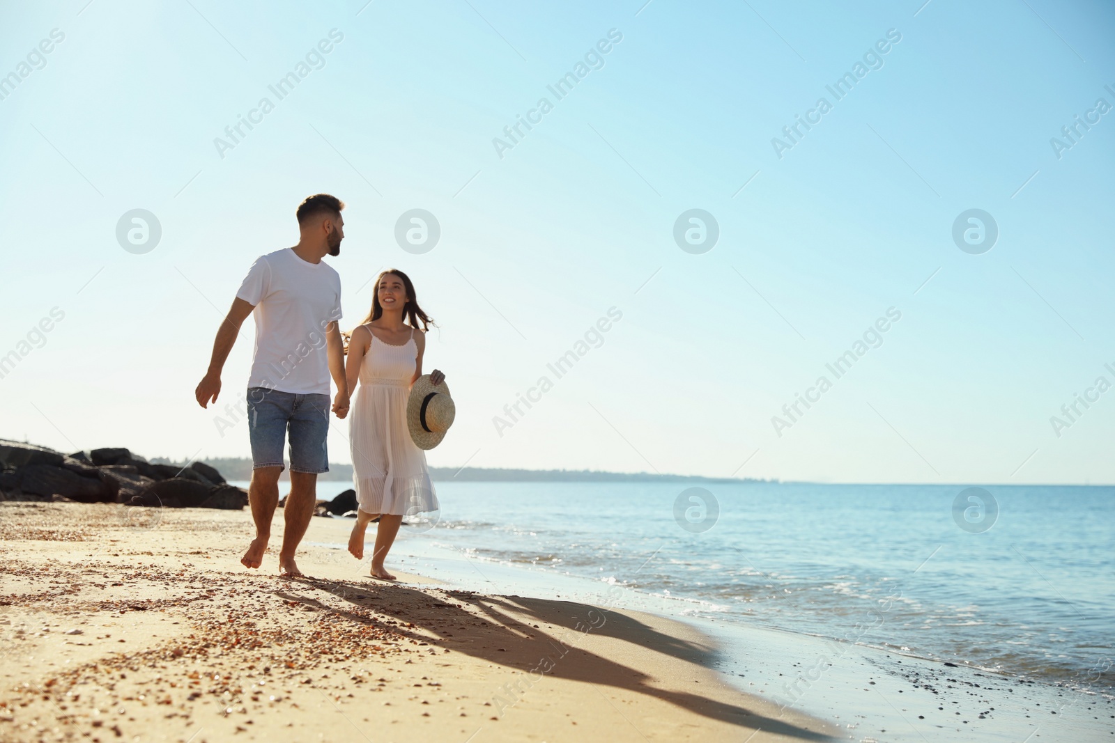 Photo of Happy young couple running on beach near sea. Honeymoon trip