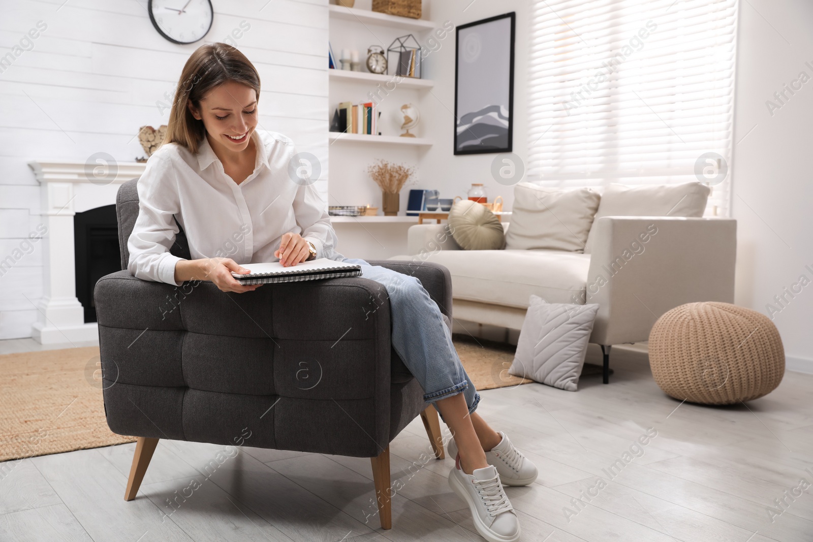 Photo of Young woman drawing in sketchbook with pencil at home, space for text