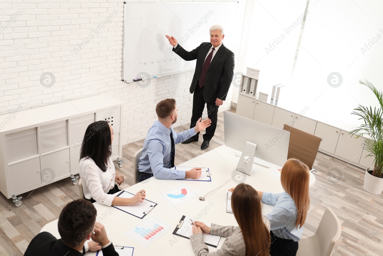 Photo of Senior business trainer working with people in office