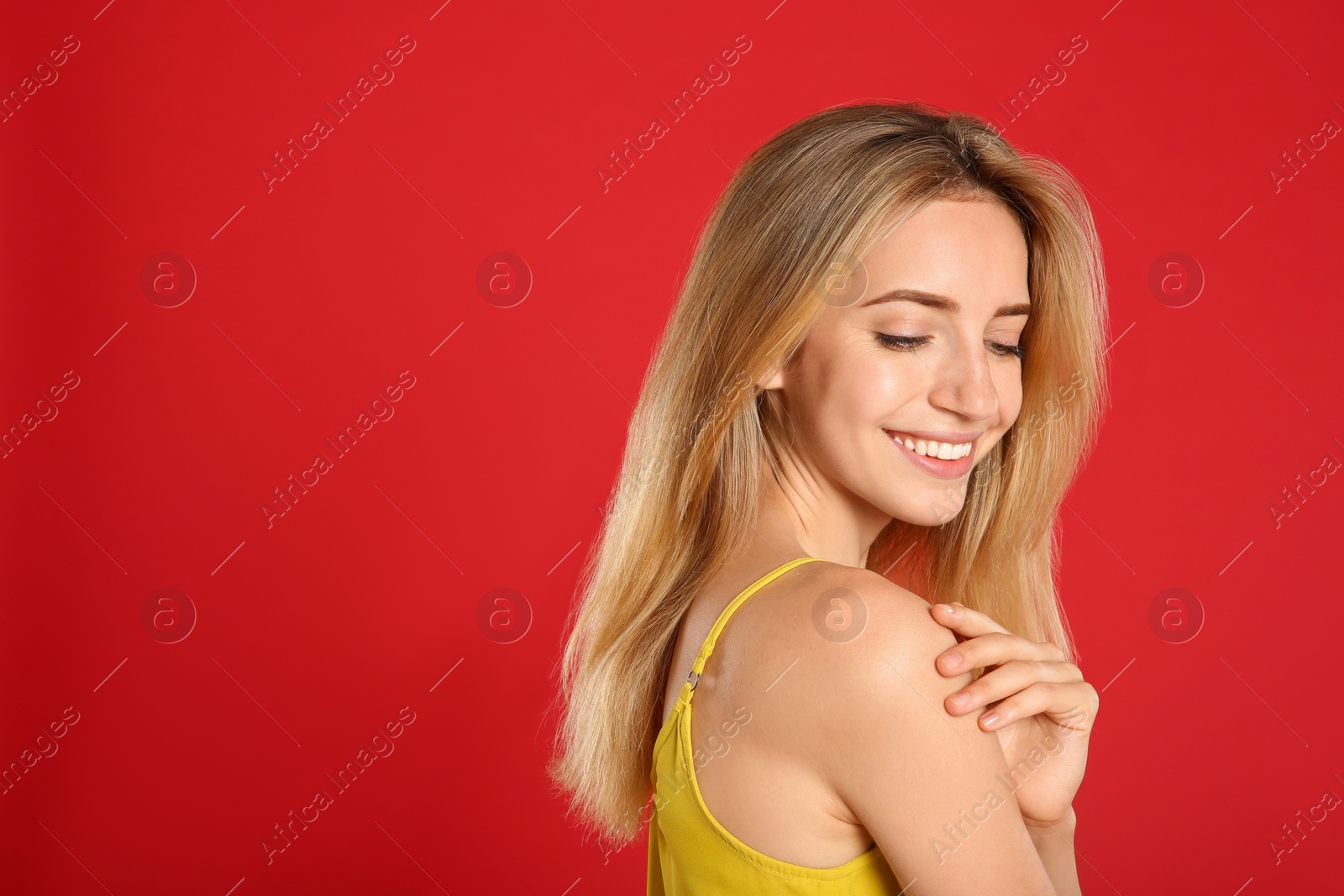 Photo of Beautiful young woman with blonde hair on red background. Space for text