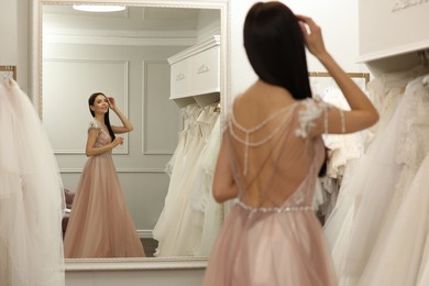 Photo of Woman trying on beautiful wedding dress in boutique