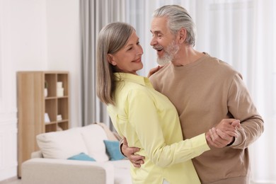 Happy affectionate senior couple dancing at home