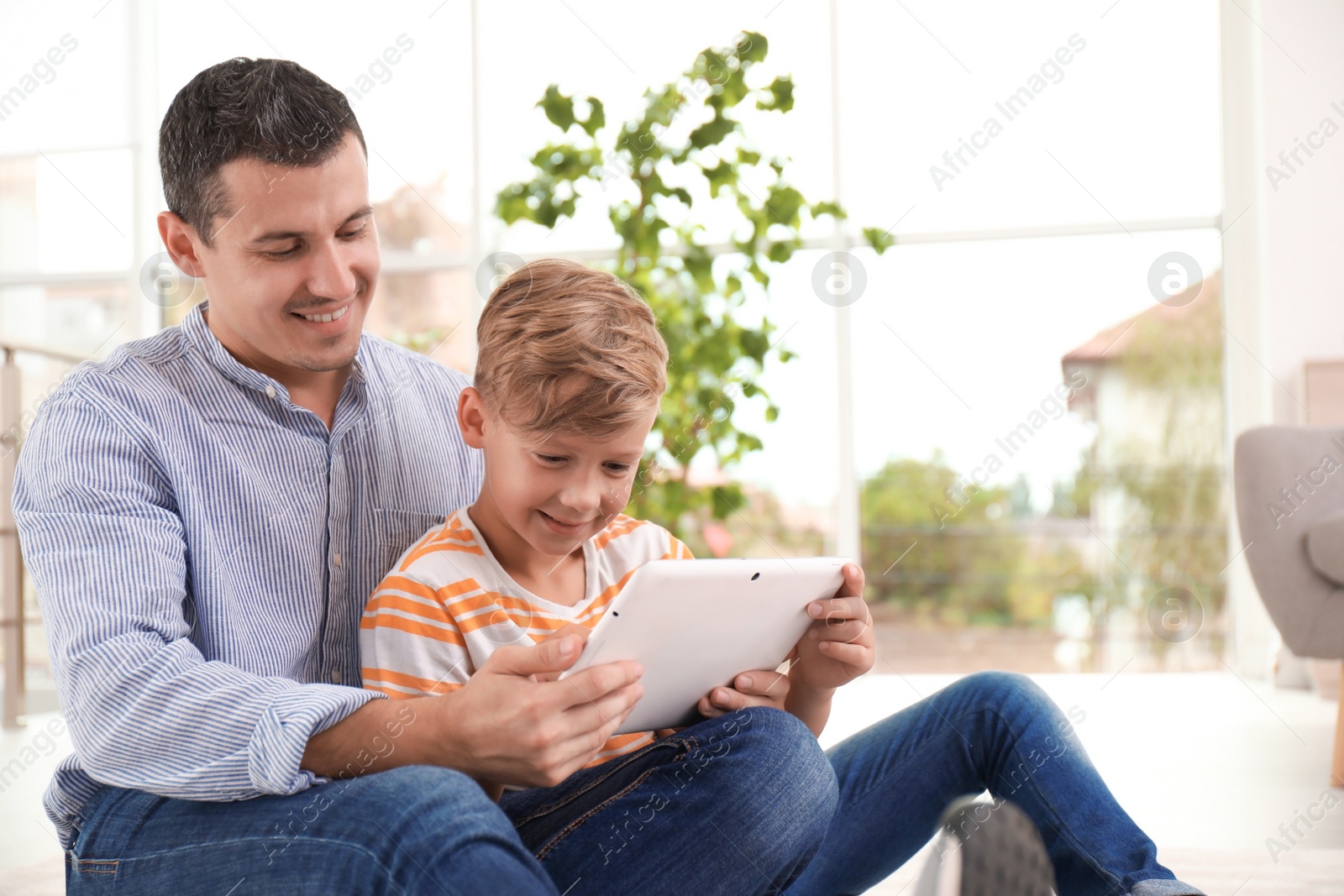 Photo of Father with child using tablet at home. Happy family