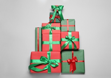 Photo of Christmas tree shape of gift boxes on light grey background, flat lay