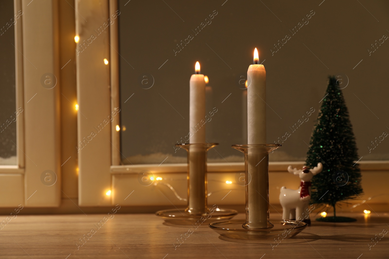 Photo of Burning candles and festive decor on window sill indoors, space for text. Christmas eve