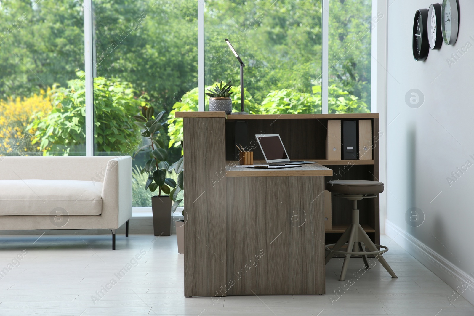 Photo of Stylish modern wooden desk with laptop indoors. Receptionist workplace