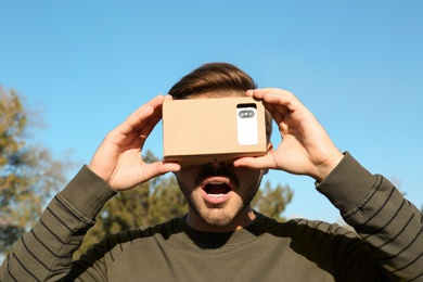 Young man using cardboard virtual reality headset outdoors