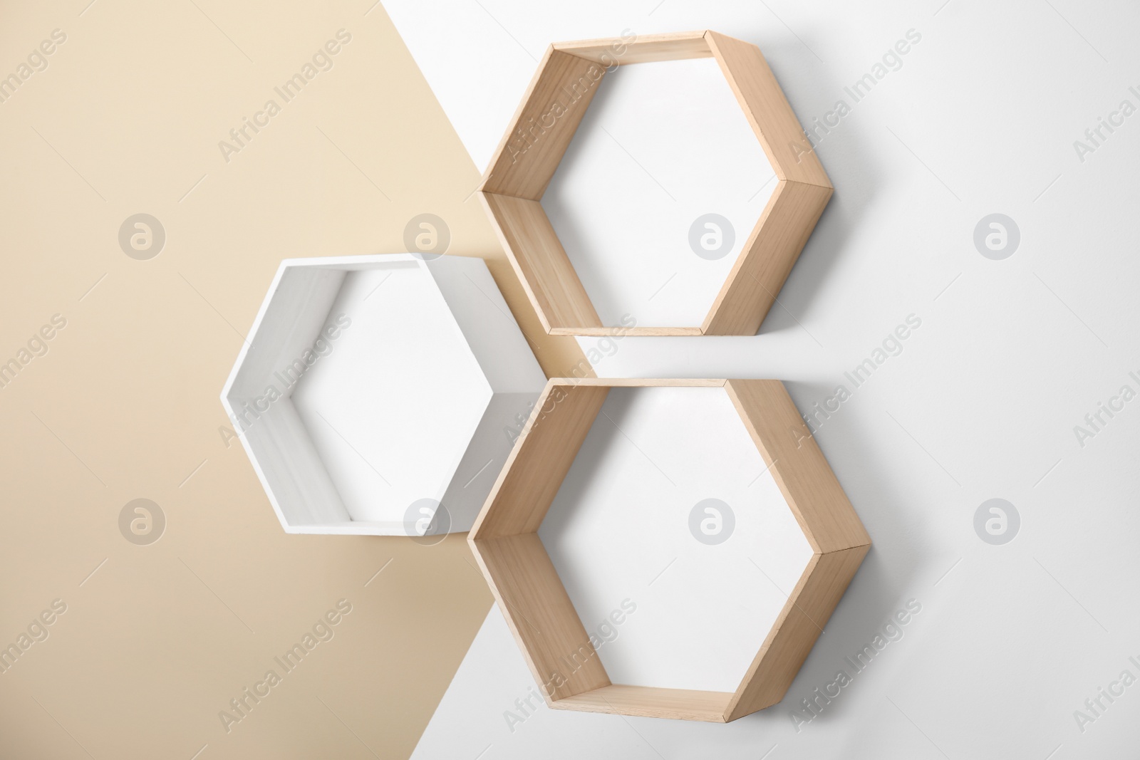 Photo of Empty honeycomb shaped shelves on color wall