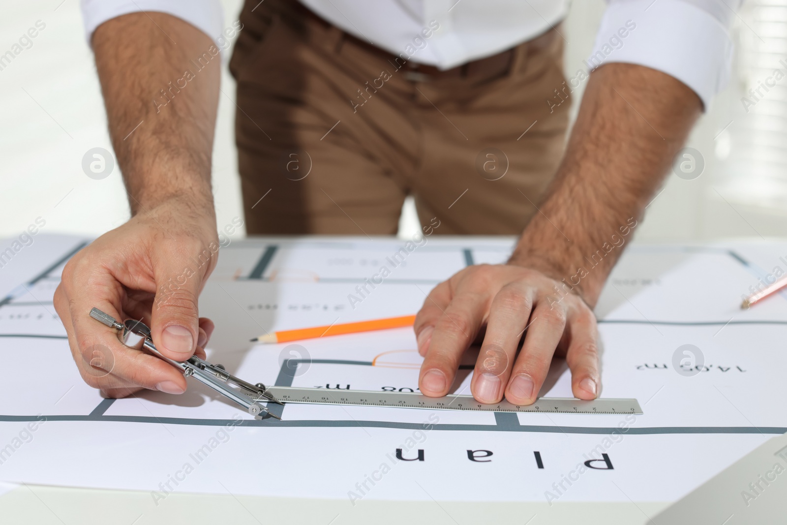 Photo of Architect working with construction drawings indoors, closeup