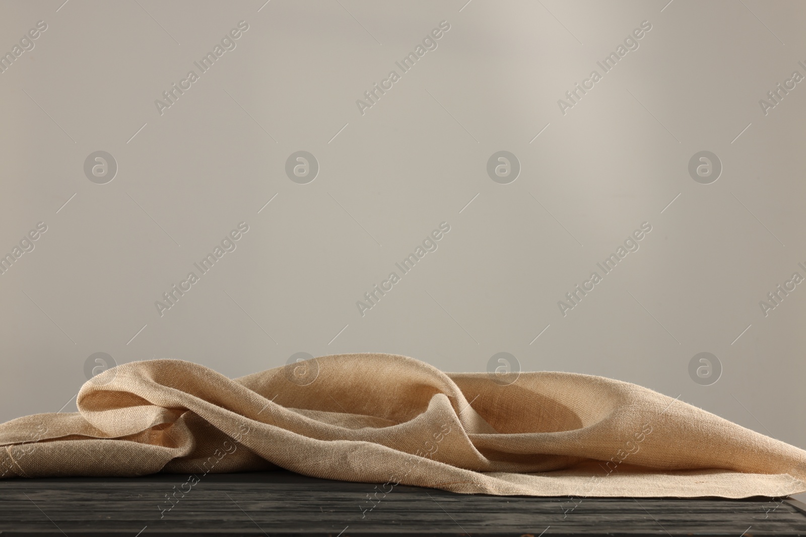 Photo of Natural burlap fabric on wooden table against light background. Space for text