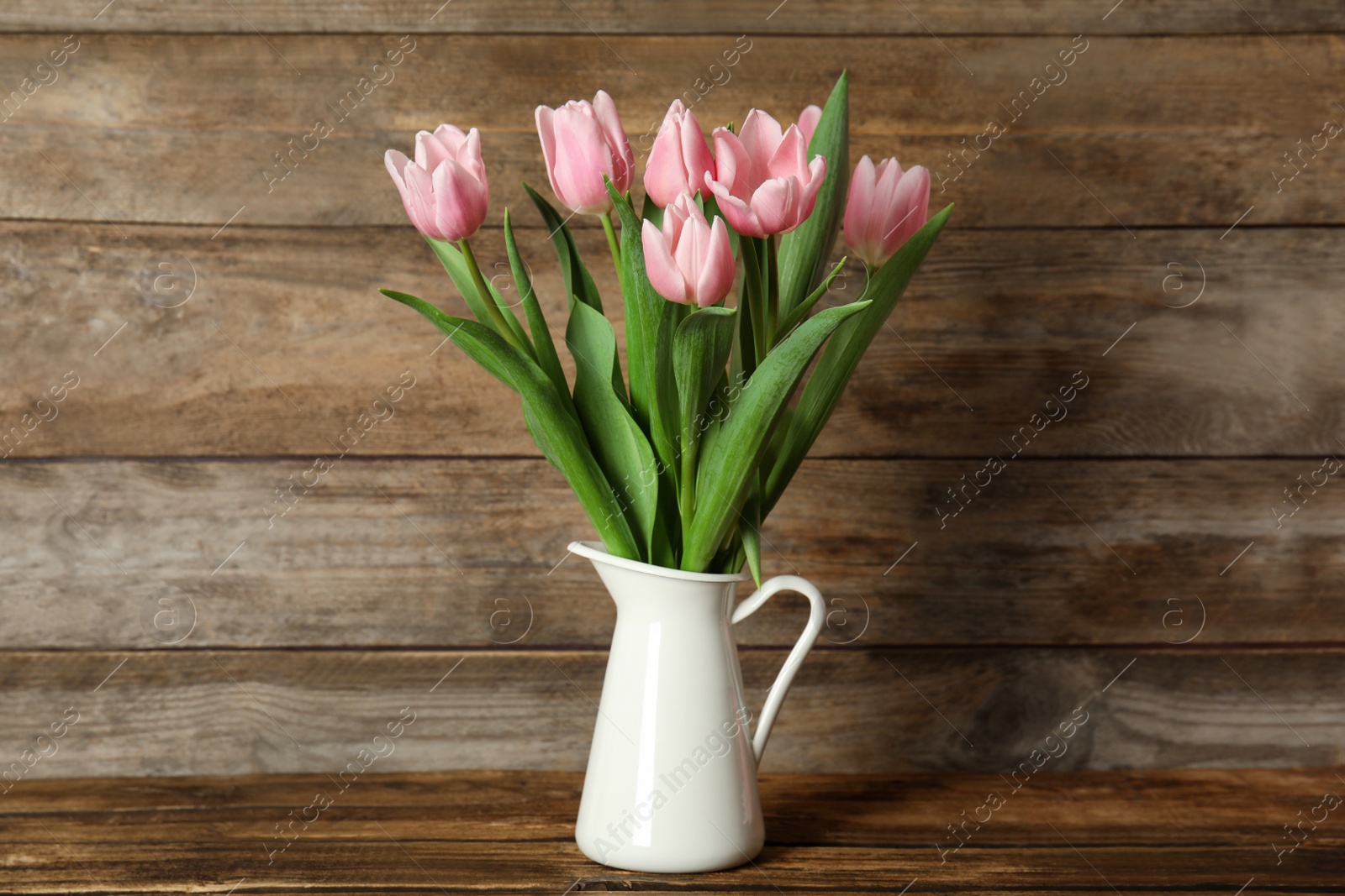 Photo of Beautiful pink spring tulips in vase on wooden table