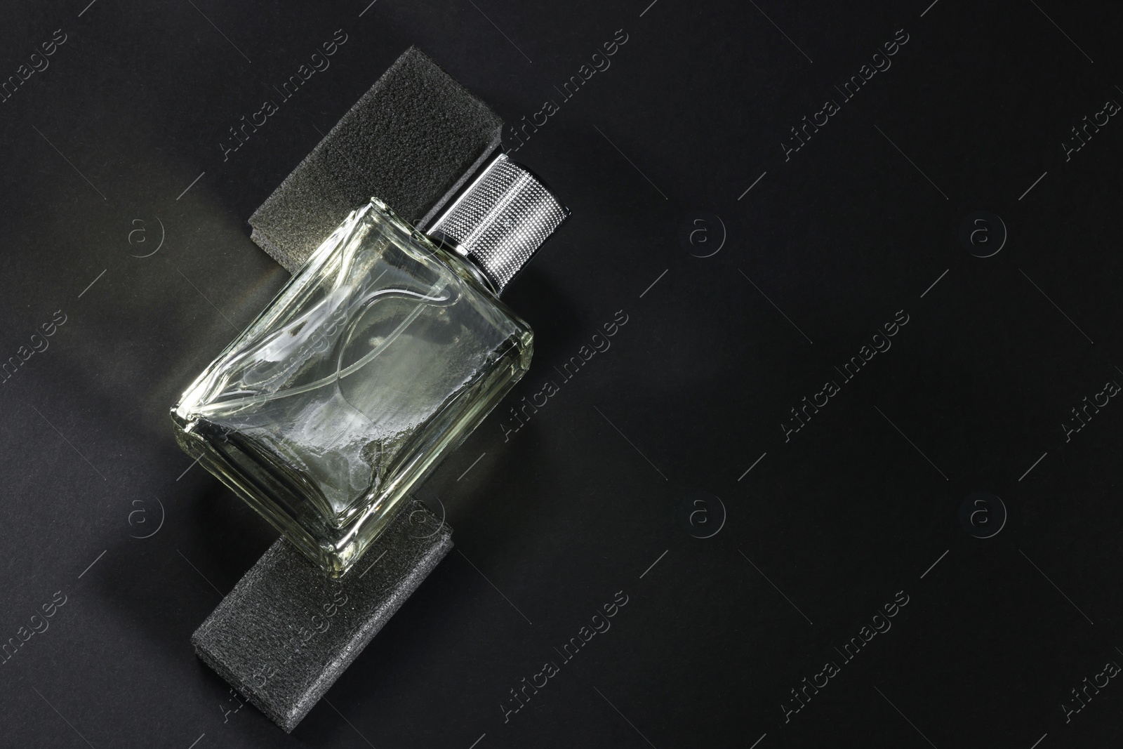 Photo of Stylish presentation of luxury men`s perfume in bottle on black background, top view. Space for text