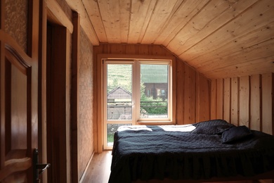 Photo of Cozy bedroom with window and wooden walls on sunny day