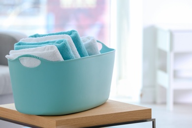 Photo of Laundry basket with clean towels on table indoors