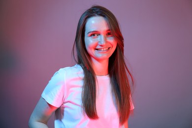 Photo of Portrait of beautiful woman in neon lights on color background