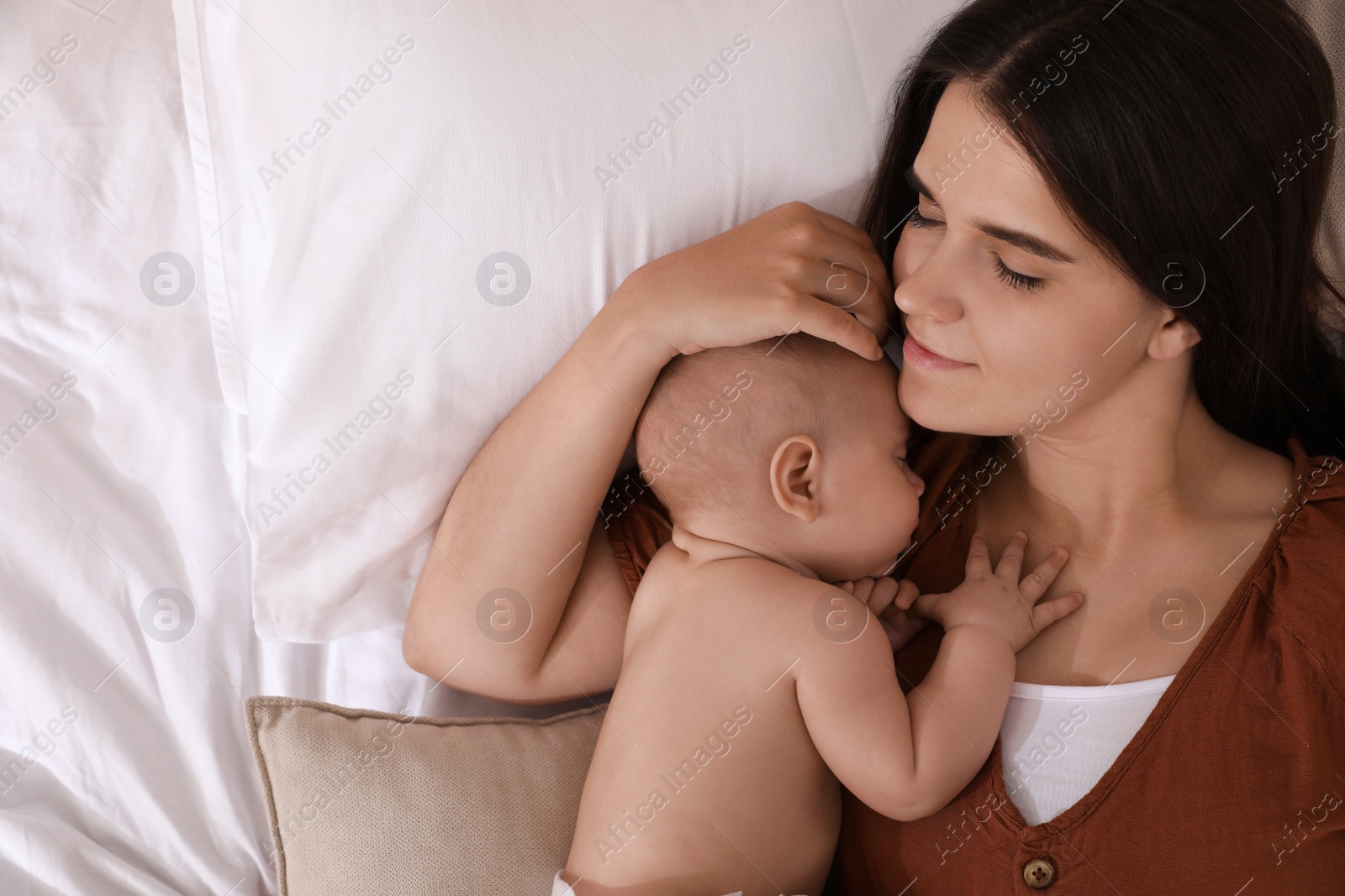 Photo of Mother with her cute baby sleeping on bed, top view