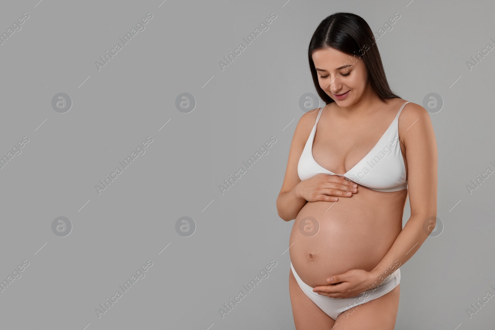 Photo of Beautiful pregnant woman in stylish comfortable underwear on grey background, space for text