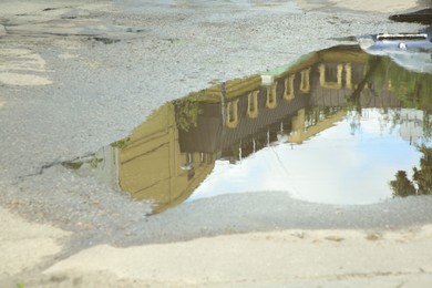 Reflection of buildings in puddle on asphalt