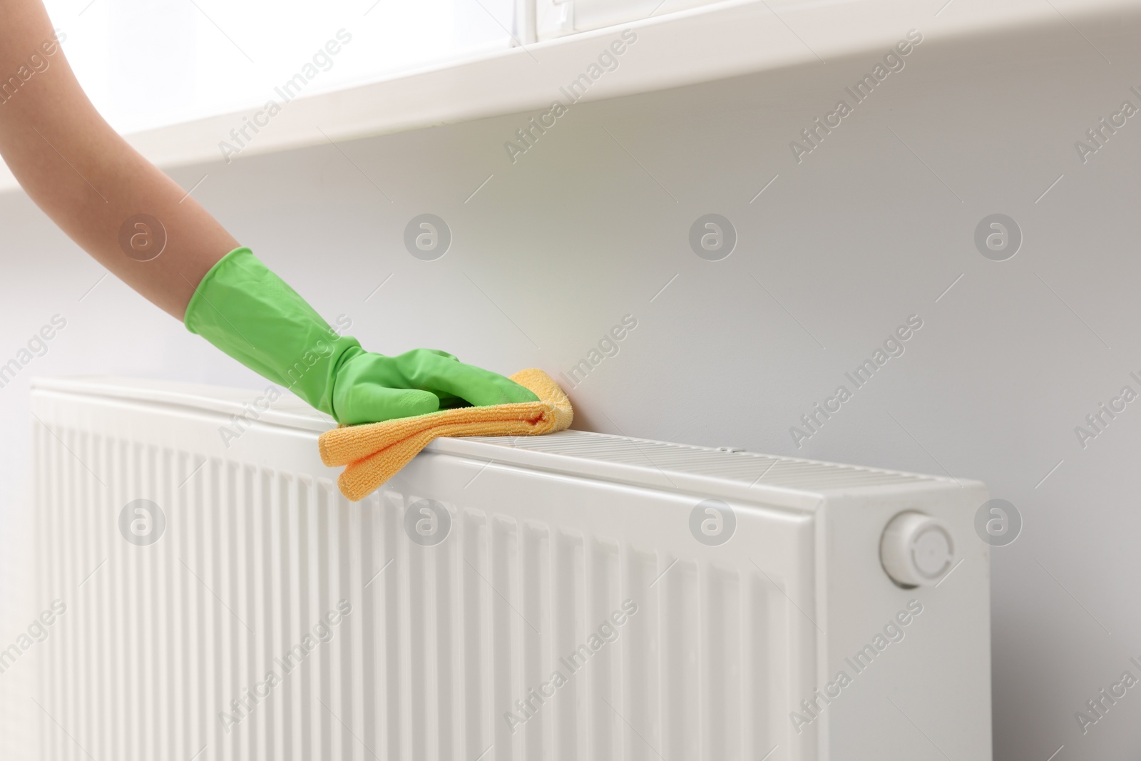 Photo of Woman cleaning radiator with rag indoors, closeup. Space for text