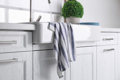 Photo of Clean striped towel on sink in kitchen