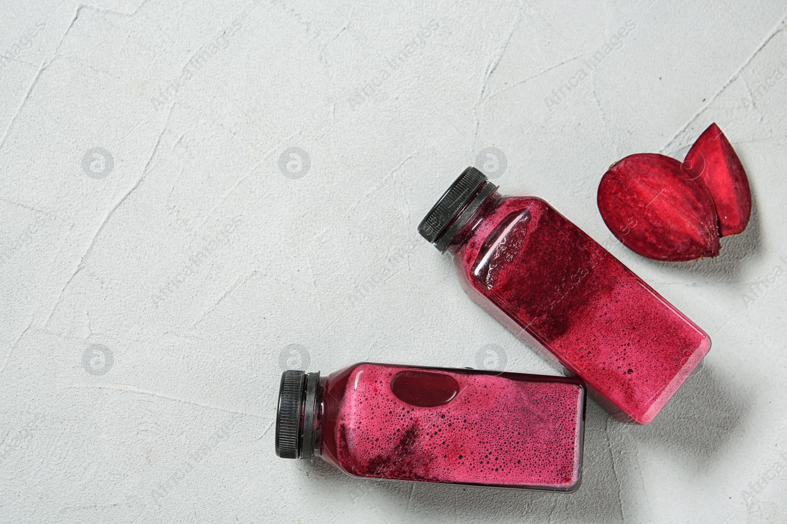 Photo of Bottles of tasty beet smoothies on light background with space for text, top view