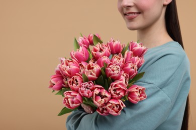 Photo of Happy woman with beautiful bouquet on beige background, closeup