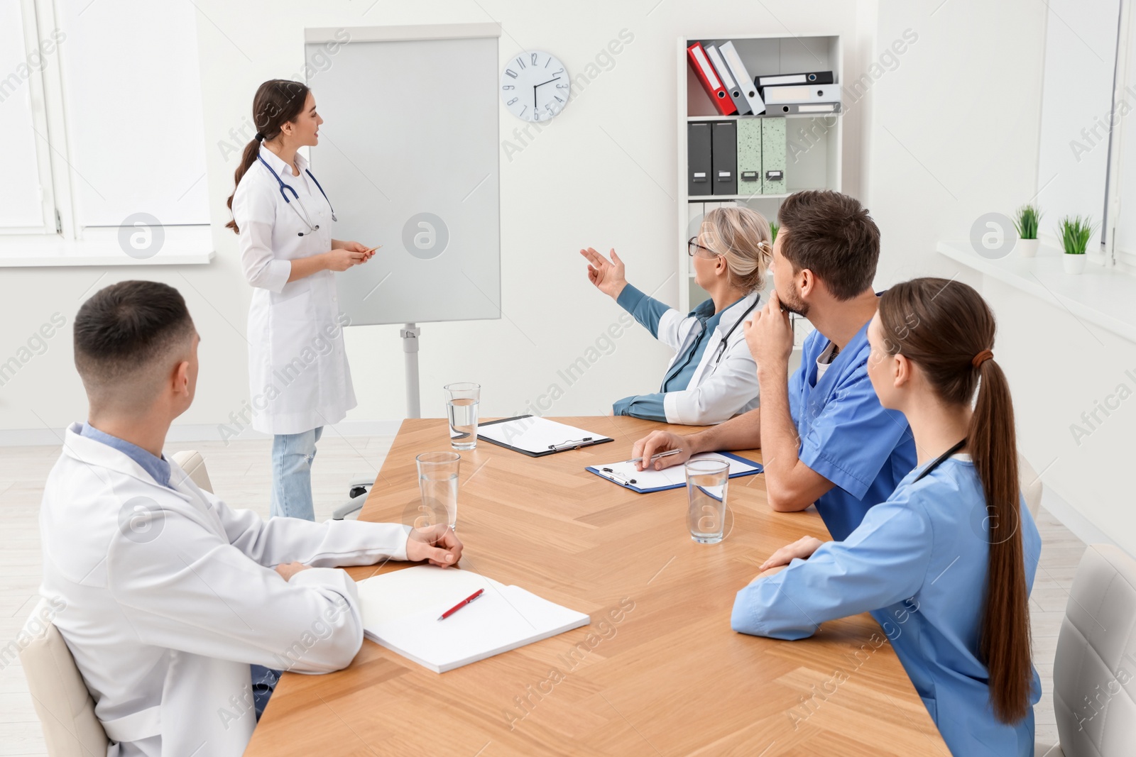 Photo of Doctor giving lecture near flipchart in conference room